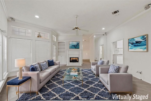 living room with built in features, ornamental molding, and ceiling fan