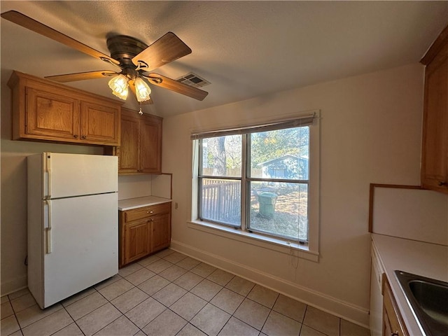 kitchen with ceiling fan, white fridge, light tile patterned floors, and sink