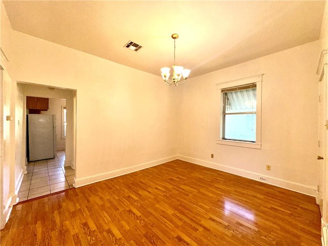 unfurnished room with hardwood / wood-style flooring, a notable chandelier, and a textured ceiling