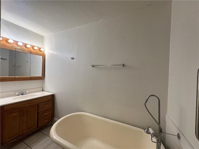 bathroom featuring tile patterned floors, a tub, vanity, and a textured ceiling