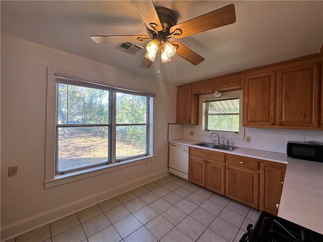 kitchen featuring dishwasher, sink, ceiling fan, light tile patterned floors, and a textured ceiling