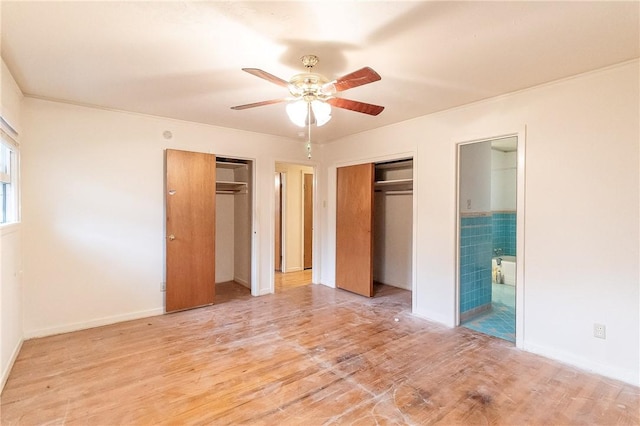 unfurnished bedroom with multiple closets, ensuite bathroom, ceiling fan, and light hardwood / wood-style flooring