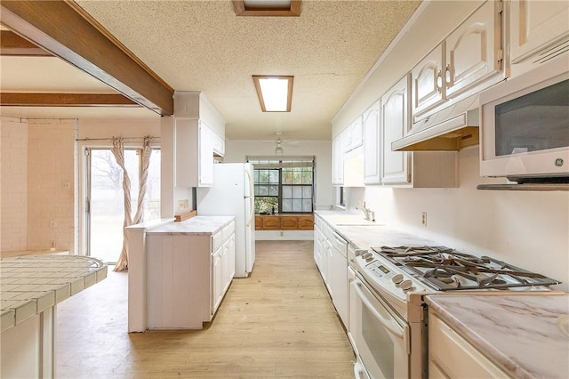 kitchen featuring white cabinetry, sink, white appliances, a healthy amount of sunlight, and light wood-type flooring