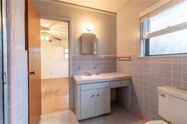 bathroom with toilet, tile walls, vanity, hardwood / wood-style flooring, and ceiling fan