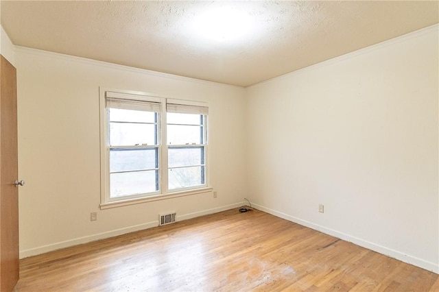 spare room featuring crown molding, light hardwood / wood-style flooring, and a textured ceiling