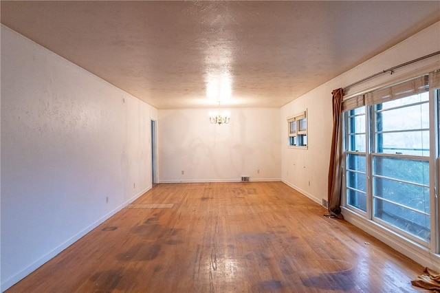 spare room featuring hardwood / wood-style flooring, a textured ceiling, and a chandelier