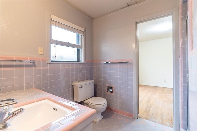 bathroom featuring toilet, tile patterned flooring, and tile walls