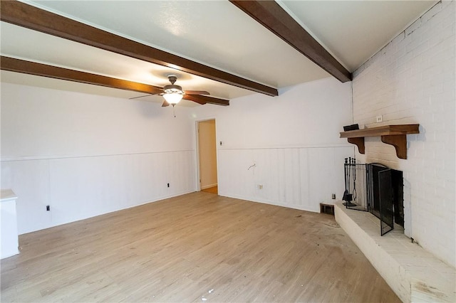 unfurnished living room featuring a fireplace, beam ceiling, light hardwood / wood-style flooring, and ceiling fan