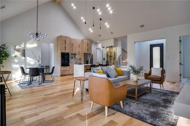 living room with high vaulted ceiling, light hardwood / wood-style floors, and an inviting chandelier