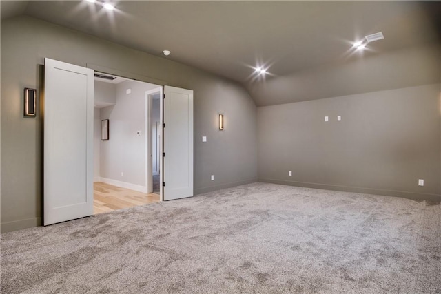 spare room with light carpet and vaulted ceiling