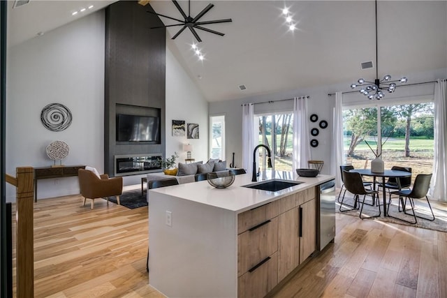 kitchen with a kitchen island with sink, sink, high vaulted ceiling, light hardwood / wood-style flooring, and dishwasher