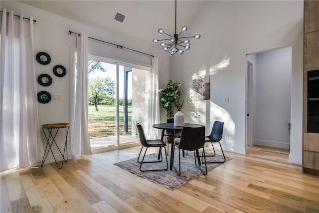 dining area featuring an inviting chandelier, high vaulted ceiling, and light hardwood / wood-style flooring