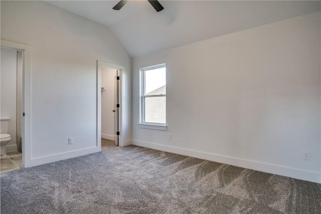 unfurnished bedroom featuring ensuite bathroom, light colored carpet, ceiling fan, a spacious closet, and lofted ceiling