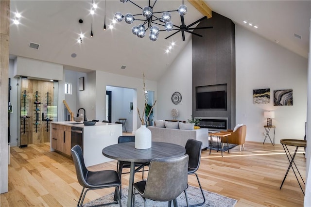 dining room featuring light hardwood / wood-style floors, sink, high vaulted ceiling, and a chandelier