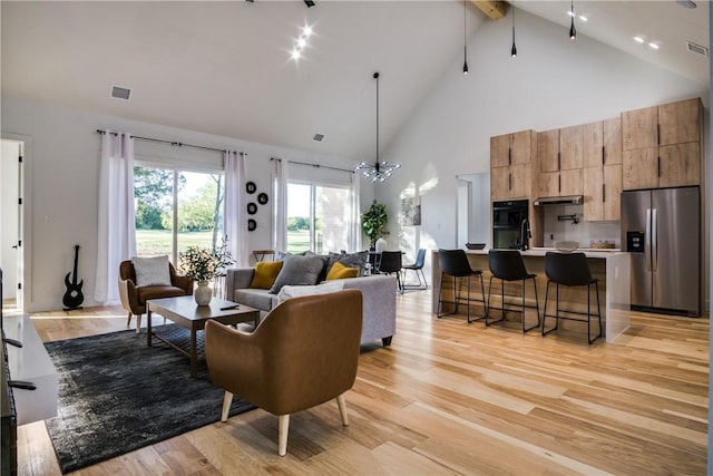 living room with sink, beam ceiling, high vaulted ceiling, a notable chandelier, and light hardwood / wood-style floors