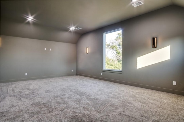 carpeted spare room featuring vaulted ceiling