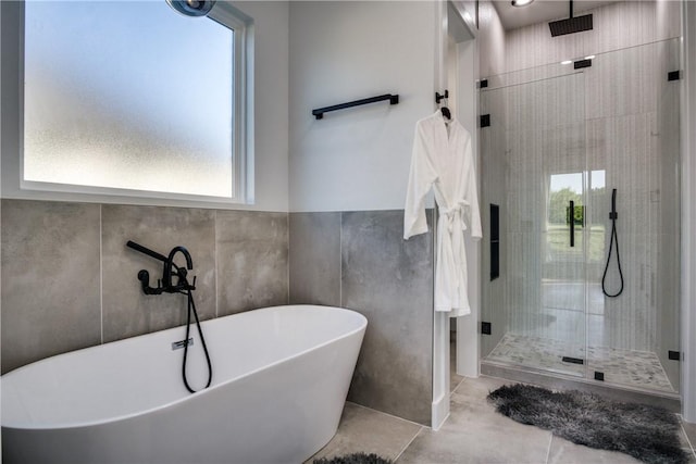 bathroom with tile patterned flooring, tile walls, and plus walk in shower