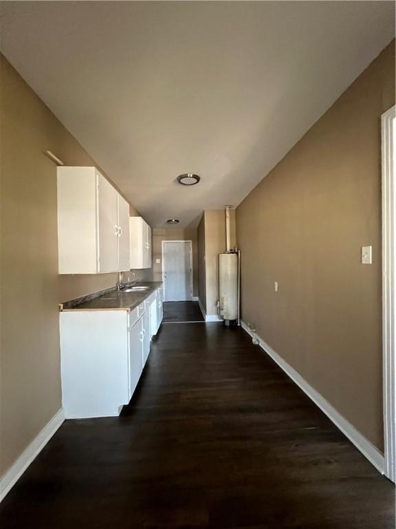 kitchen with white cabinets, dark hardwood / wood-style flooring, sink, and water heater