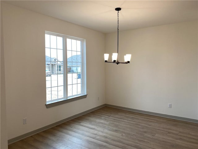 unfurnished dining area with wood-type flooring, a wealth of natural light, and a chandelier