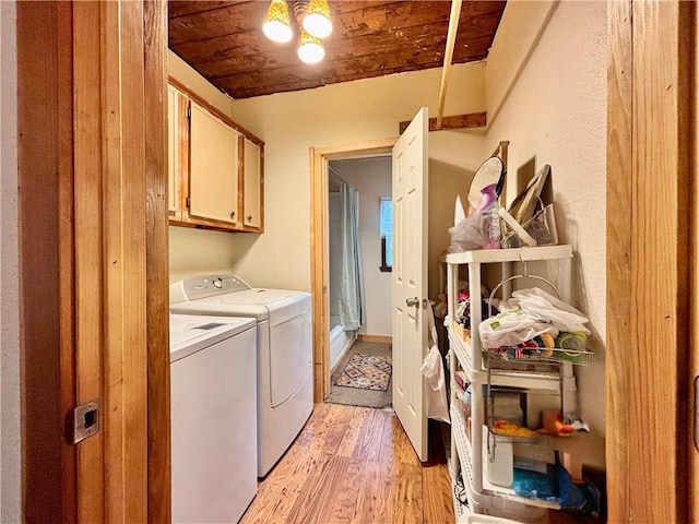 laundry area featuring wood ceiling, cabinet space, light wood finished floors, and washing machine and clothes dryer