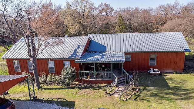 view of front of house with a porch, metal roof, board and batten siding, and a front yard