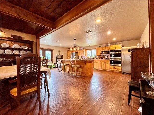 dining room with plenty of natural light, visible vents, dark wood finished floors, and a textured ceiling