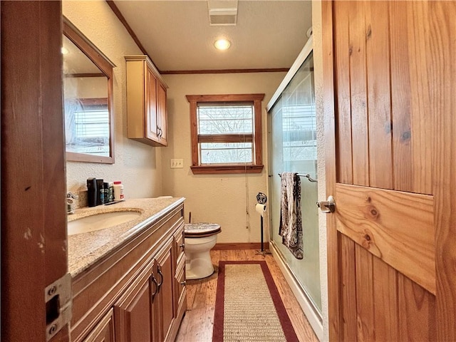 full bathroom featuring toilet, wood finished floors, vanity, a shower stall, and crown molding