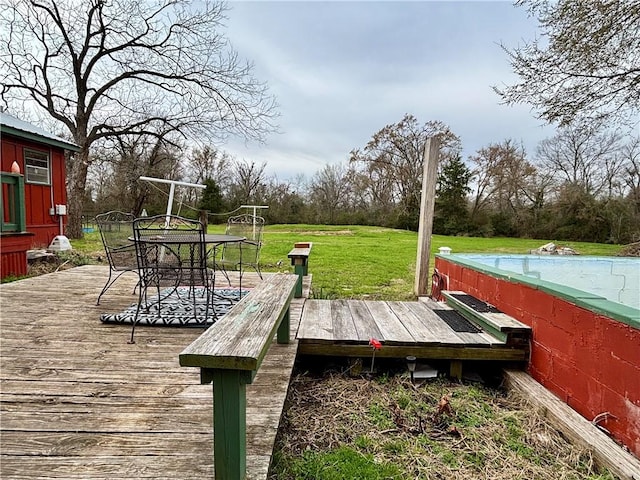 view of dock with outdoor dining area, a wooden deck, and a lawn