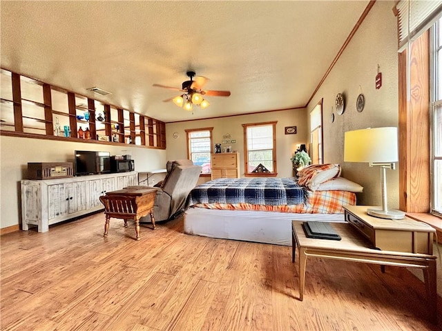 living room with visible vents, a ceiling fan, wood finished floors, crown molding, and a textured ceiling