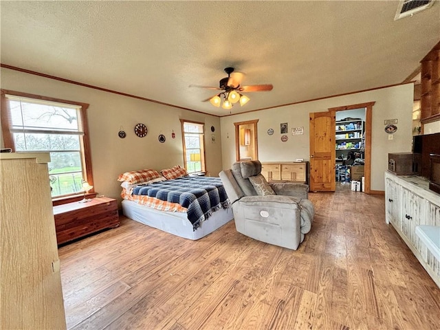 bedroom featuring a textured ceiling, visible vents, and light wood-style floors