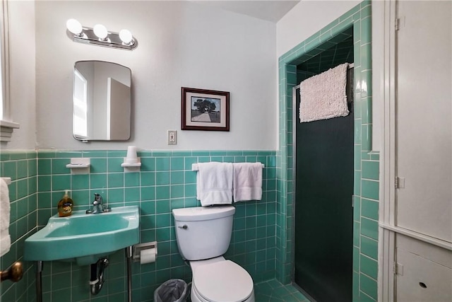 bathroom with a shower, sink, tile walls, and toilet