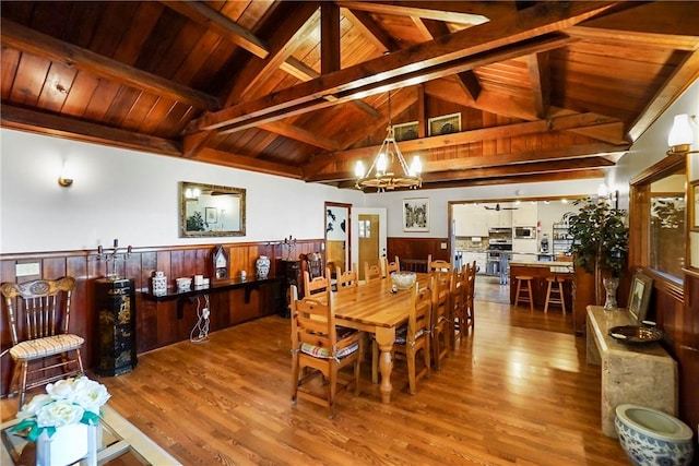 dining space with vaulted ceiling with beams, hardwood / wood-style floors, wooden ceiling, and an inviting chandelier