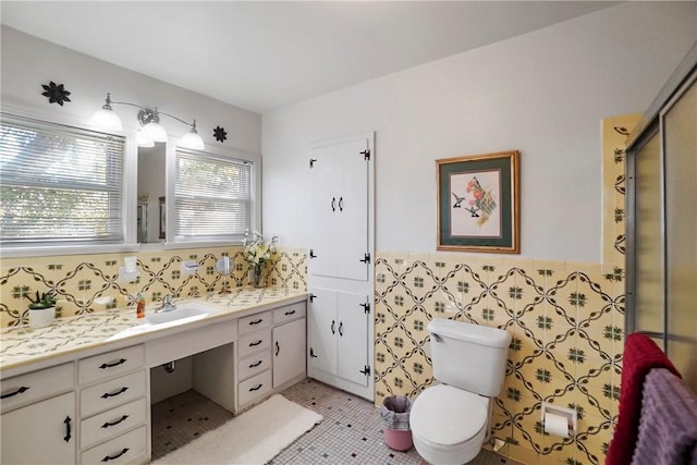 bathroom featuring vanity, a shower with door, tile patterned floors, toilet, and tile walls