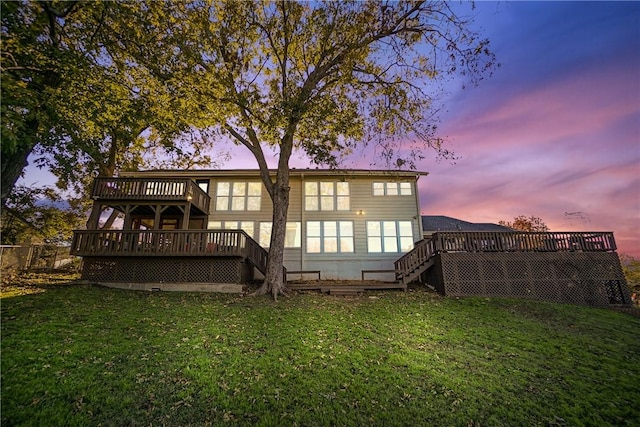 back house at dusk featuring a lawn and a deck