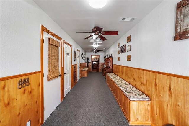 hall with dark carpet and wooden walls