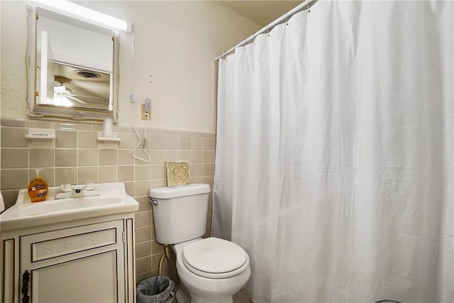 bathroom with vanity, toilet, and tile walls