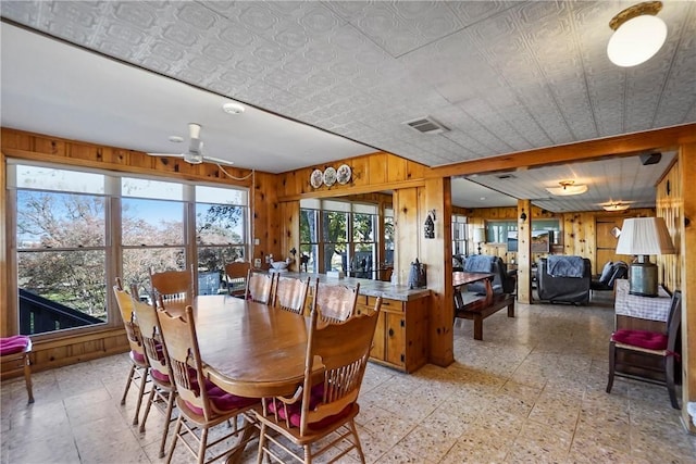 dining area featuring ceiling fan and wooden walls