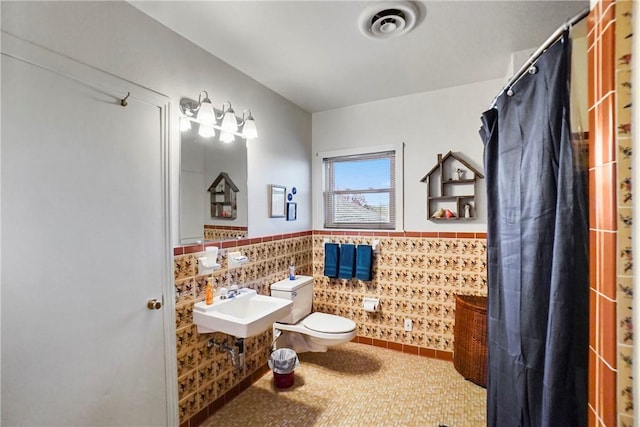 bathroom featuring a shower with curtain, toilet, tile walls, and sink