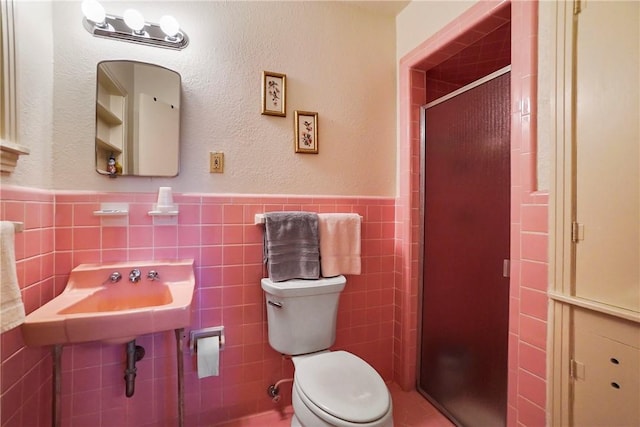 bathroom with tile walls, sink, an enclosed shower, and toilet