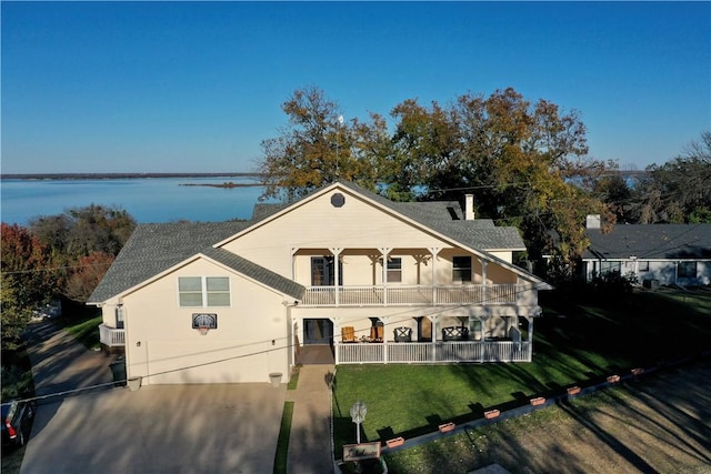 view of front facade featuring covered porch, a balcony, a front lawn, and a water view