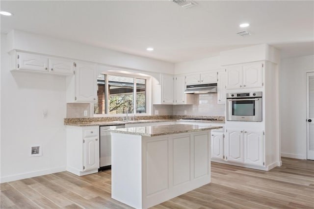 kitchen featuring a center island, white cabinetry, stainless steel appliances, and light hardwood / wood-style flooring