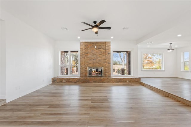 unfurnished living room featuring hardwood / wood-style flooring, a brick fireplace, and ceiling fan