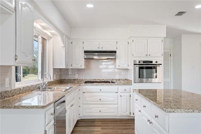 kitchen with light stone countertops, sink, dark hardwood / wood-style floors, white cabinets, and appliances with stainless steel finishes