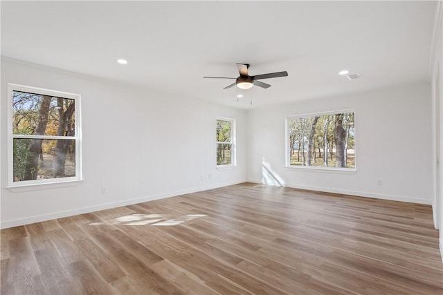 empty room with hardwood / wood-style floors, ceiling fan, and a healthy amount of sunlight