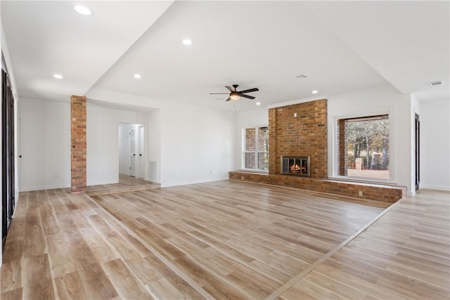 unfurnished living room featuring ceiling fan, light hardwood / wood-style floors, and a brick fireplace