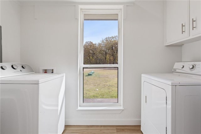 clothes washing area featuring separate washer and dryer, a wealth of natural light, cabinets, and light hardwood / wood-style floors