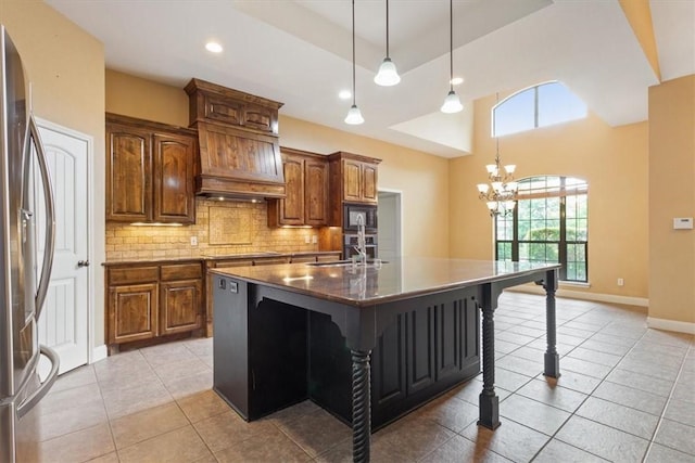 kitchen with a kitchen breakfast bar, backsplash, light tile patterned floors, an island with sink, and black appliances