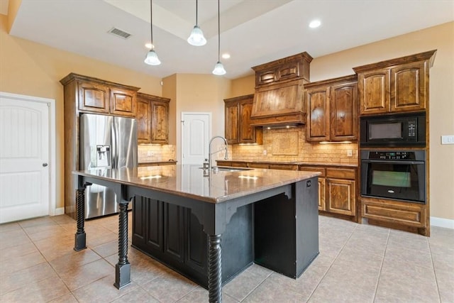 kitchen featuring sink, an island with sink, a kitchen bar, stone counters, and black appliances