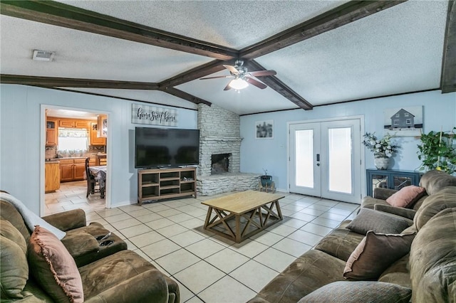 tiled living room with french doors, a textured ceiling, ceiling fan, lofted ceiling with beams, and a fireplace