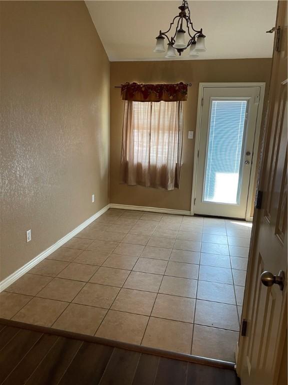 interior space with light tile patterned flooring, lofted ceiling, and a notable chandelier